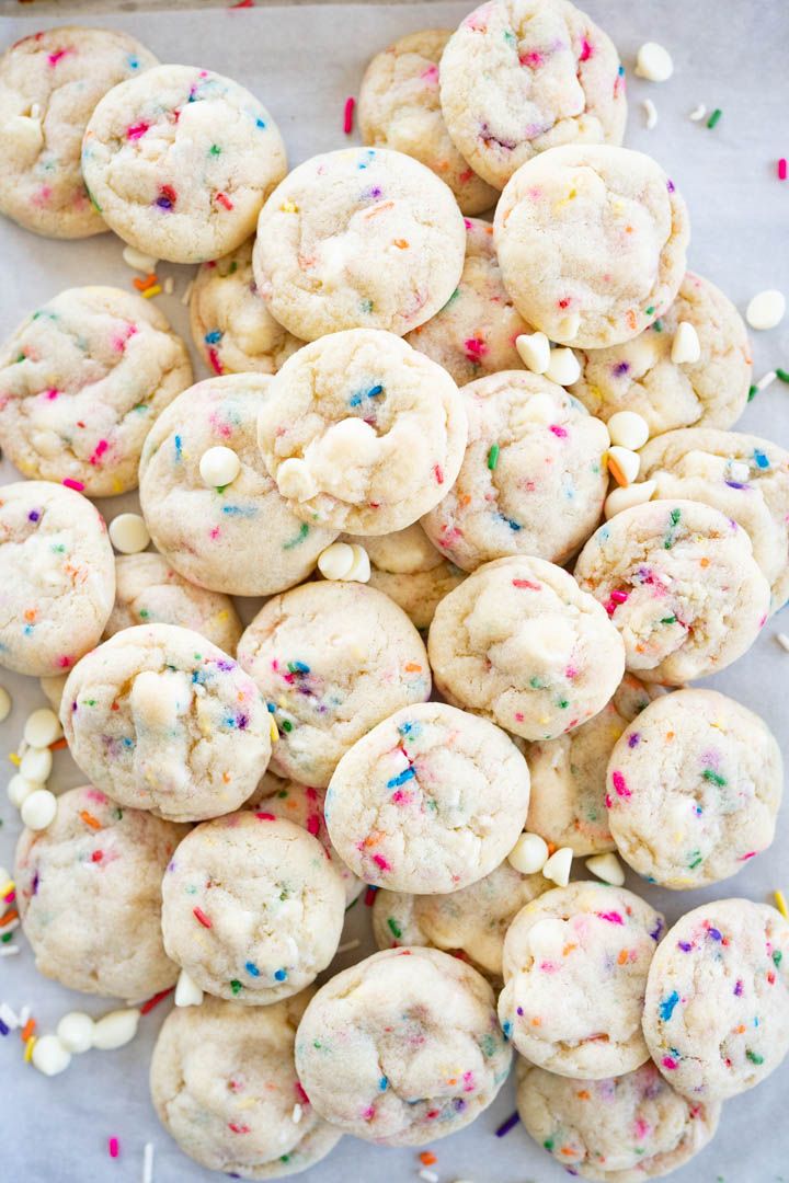 sprinkles and white chocolate chip cookies on a sheet of parchment paper with confetti