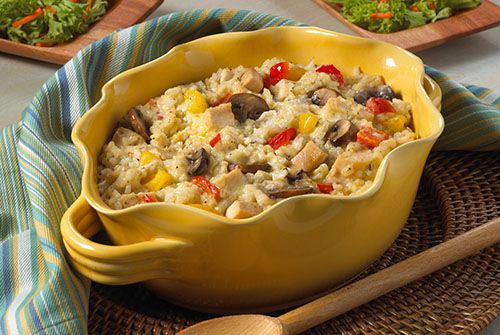 a yellow bowl filled with rice and vegetables next to two wooden spoons on a table