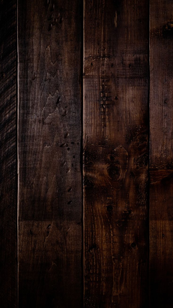 an old wooden wall with dark wood grains and peeling paint on the surface, as well as some other things