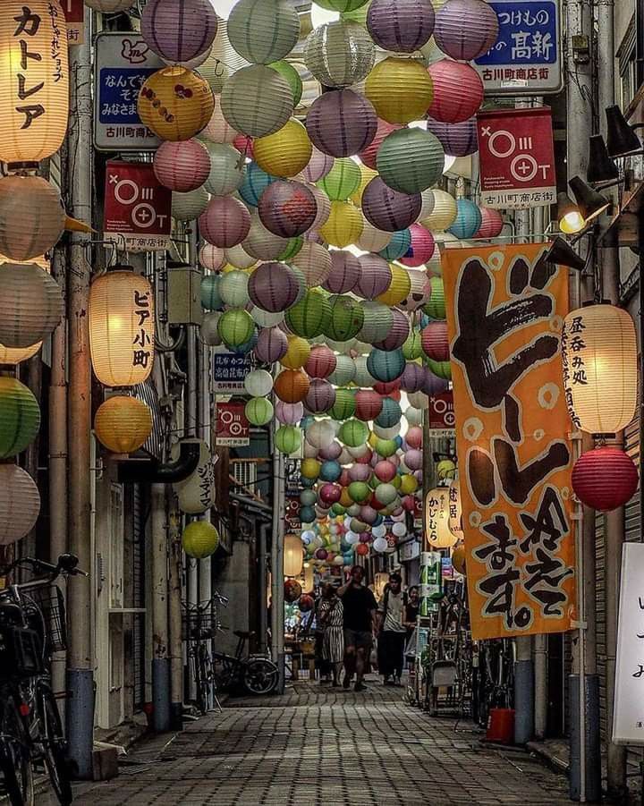 an alley way with lots of lanterns hanging from the ceiling