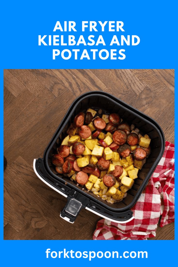 an air fryer with kielbasa and potatoes in it on a wooden table