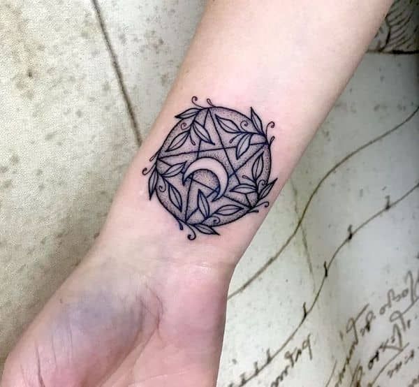 a small tattoo on the wrist of a woman's hand, with an ornamental design