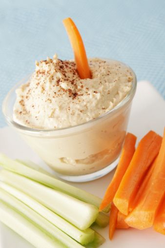 carrots, celery and dip on a white plate with blue table cloth