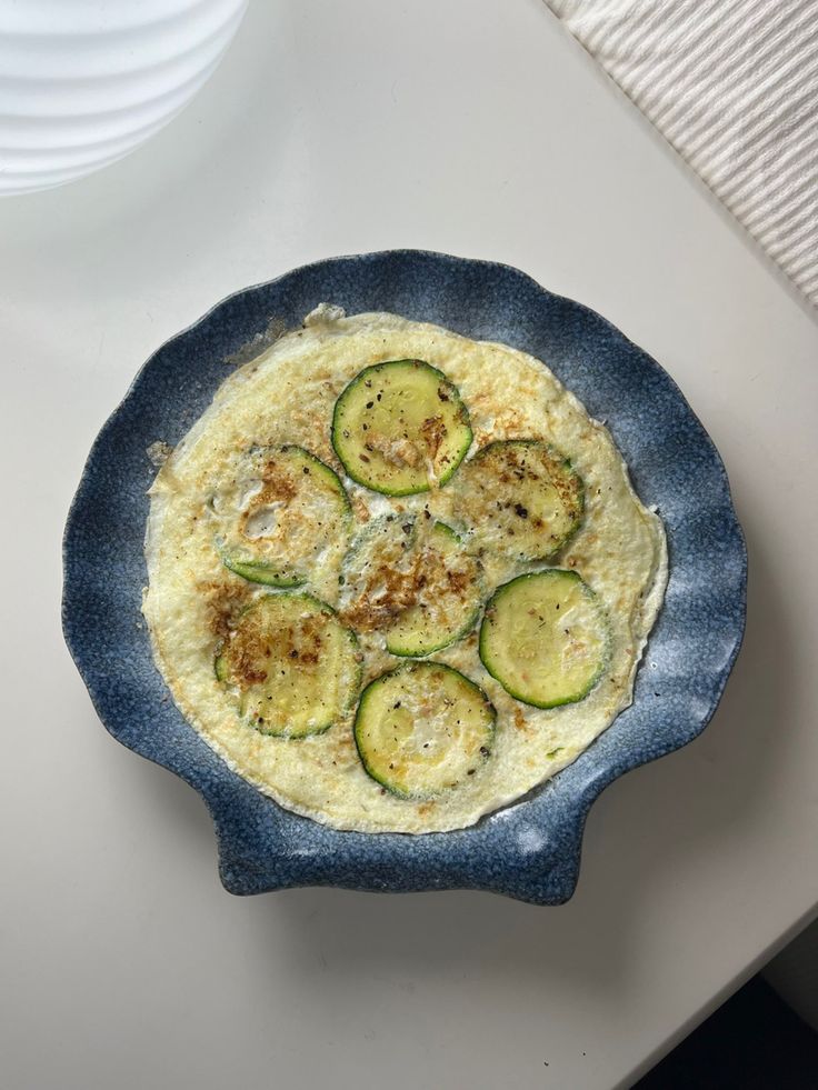 an omelet with zucchini and cheese in a blue bowl on a table