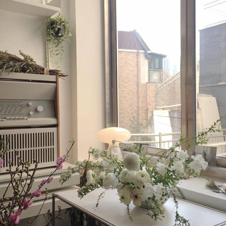 a vase with flowers sitting on top of a table next to an air conditioner