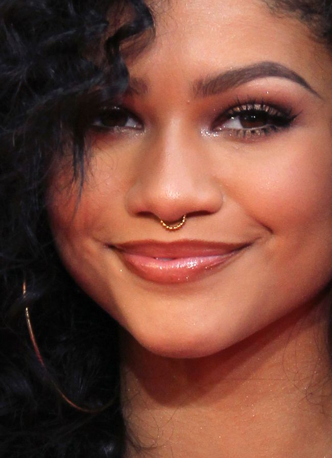 a close up of a person with a smile on her face and wearing gold hoop earrings