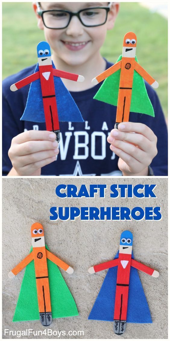 a boy holding two paper superheros with the words craft stick superheros on them