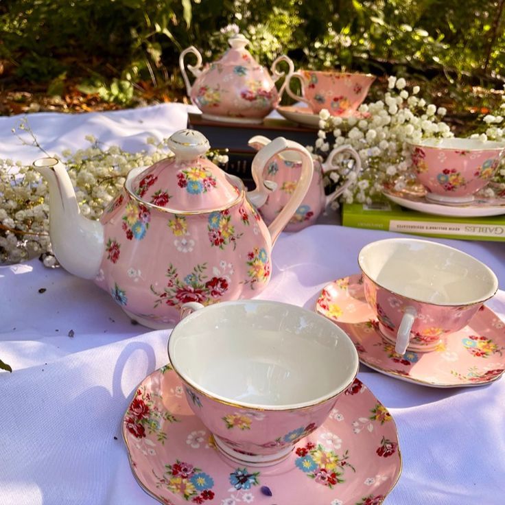 pink tea set sitting on top of a white table cloth