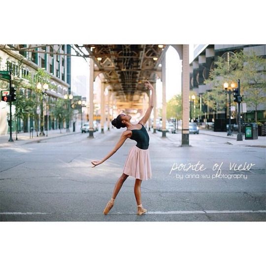 a woman is standing on one leg in the middle of an empty street and stretching her arms