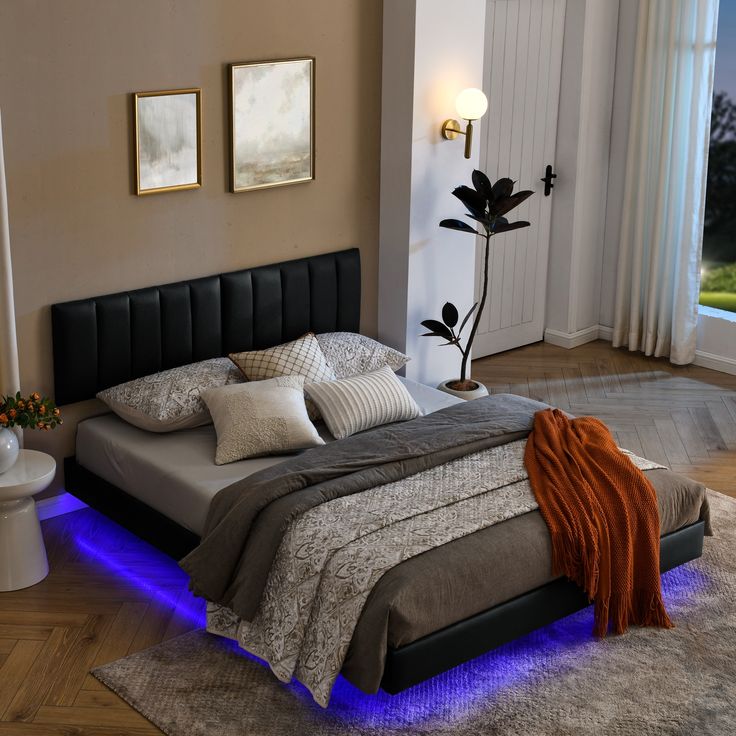 a bedroom with a large bed and blue lights on the headboard, along with pictures above it