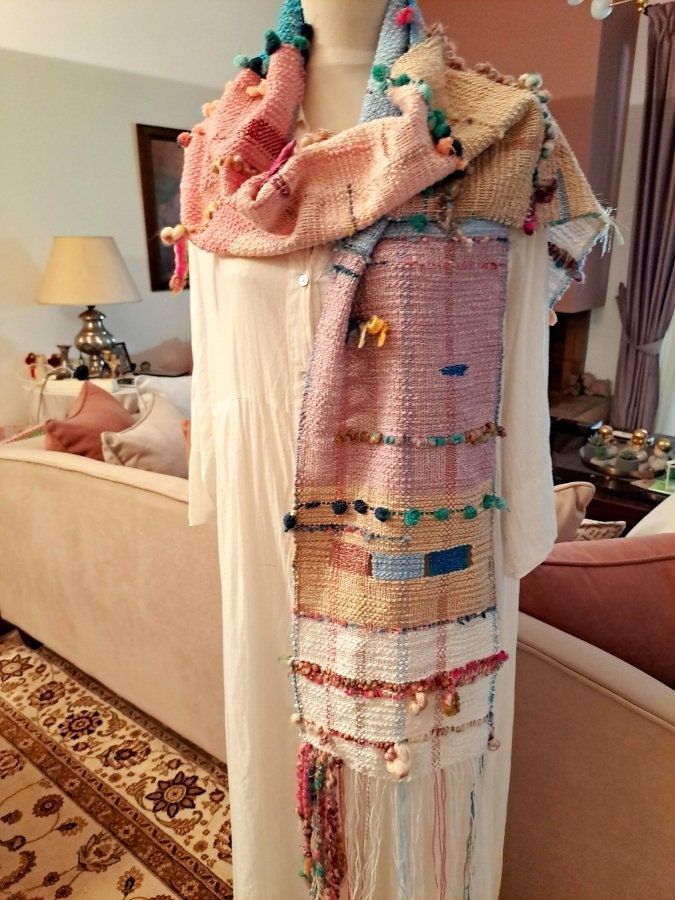 a woman's white dress with multicolored beads and tassels on it