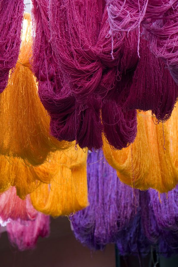 many different colored yarns are hanging from the ceiling