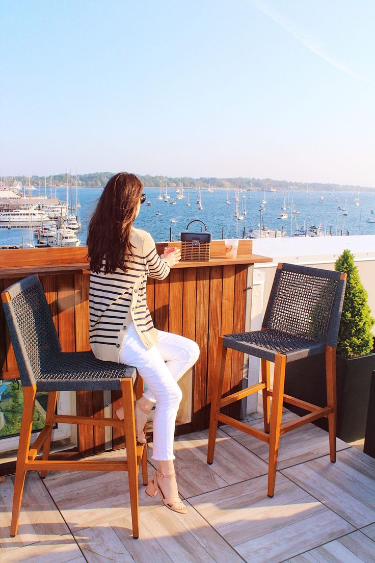 a woman sitting on top of a wooden table next to two chairs