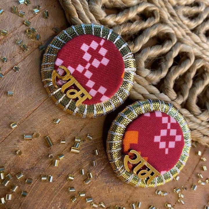 two red and gold buttons sitting on top of a piece of cloth next to a basket