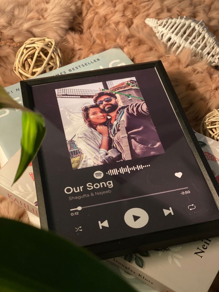 an mp3 player sitting on top of a bed next to a potted plant and books