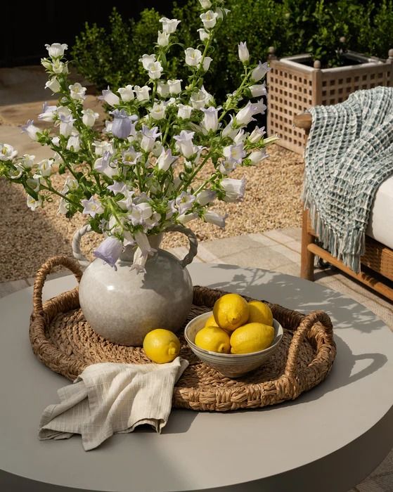 a bowl of lemons and some white flowers on a table with a wicker basket