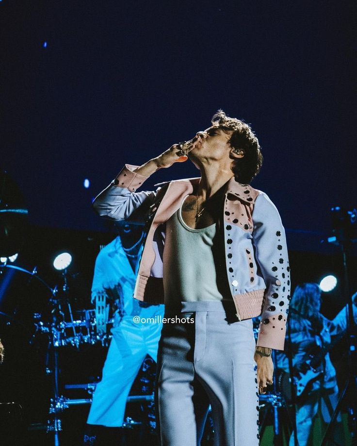 a man standing on top of a stage with his hand in his mouth while singing