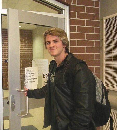 a man holding up a sign in front of a door