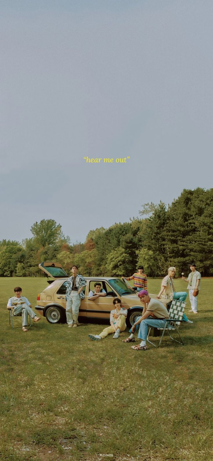 a group of people sitting on lawn chairs next to an old car in a field