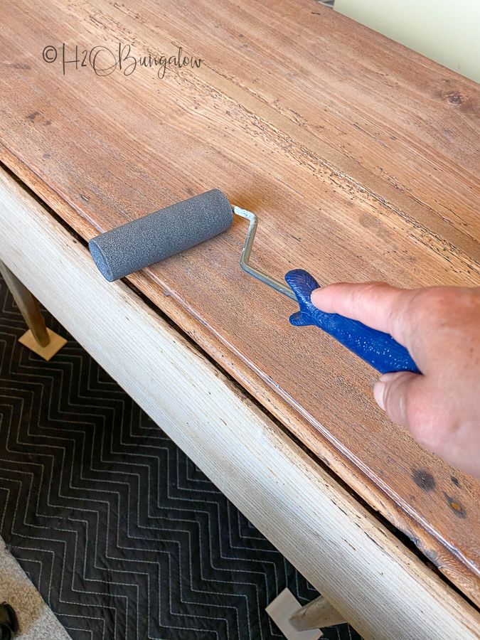 a person using a paint roller on a wooden table