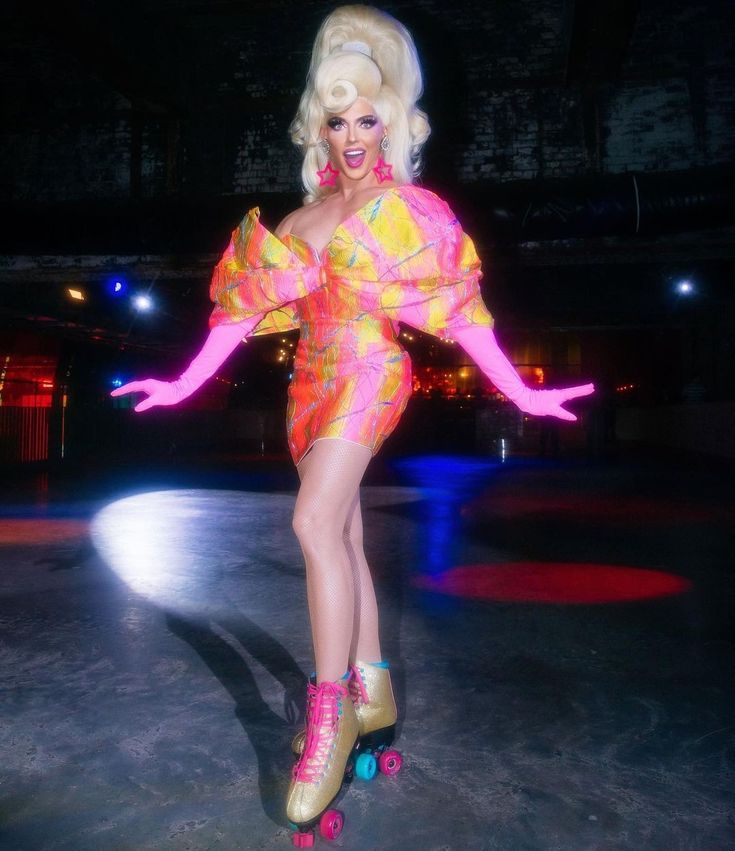 a woman in pink and yellow dress on roller skates with arms outstretched, legs spread out