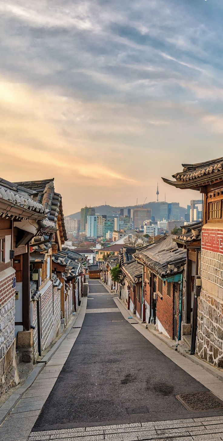 an empty street lined with old buildings in the distance, and tall buildings on either side