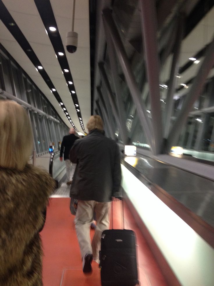 two people walking down a train platform with luggage