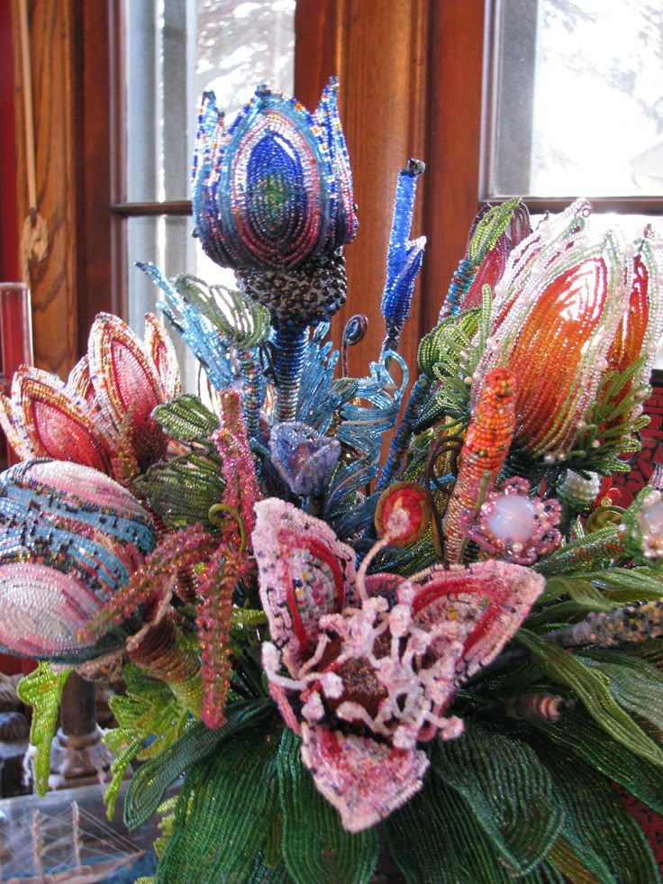 a vase filled with lots of different colored glass flowers on top of a wooden table