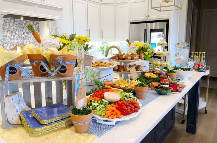 a table filled with lots of food on top of a white counter topped with pots and pans