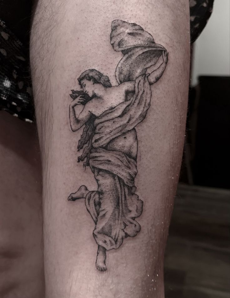 a black and white photo of a woman's leg with a tattoo on it