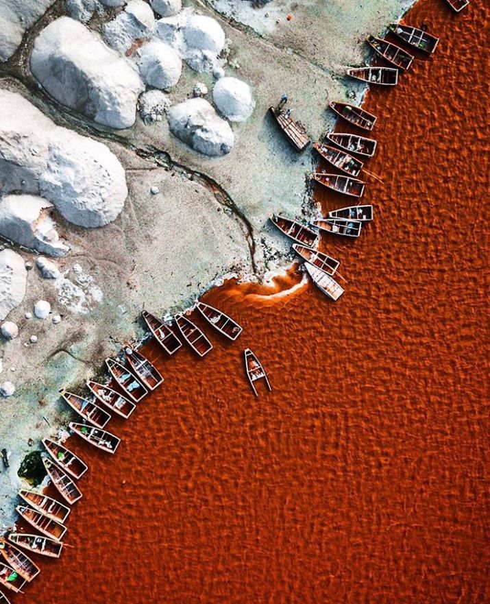 an aerial view of several boats in the water near rocks and snow covered ground,