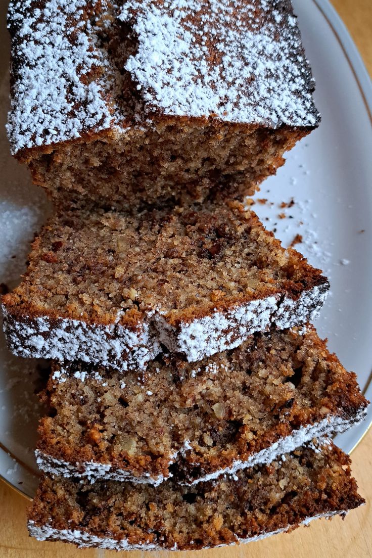 a white plate topped with slices of cake covered in powdered sugar