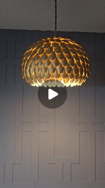 a light fixture hanging from the ceiling in a room with a white wall behind it