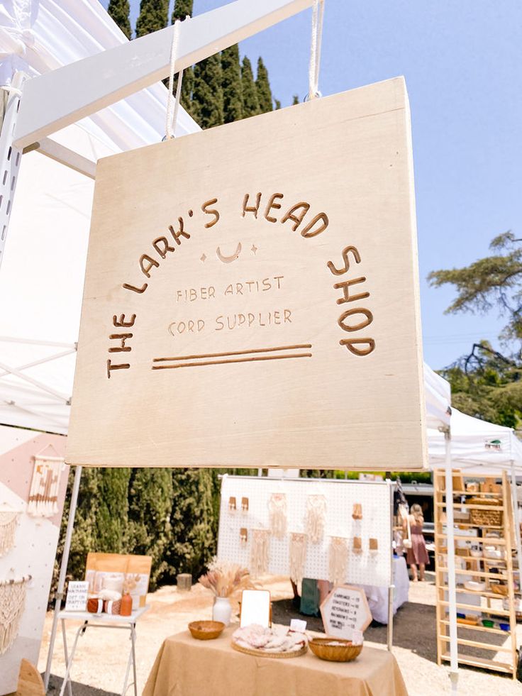 a sign that says the lark's head shop is on display at an outdoor market