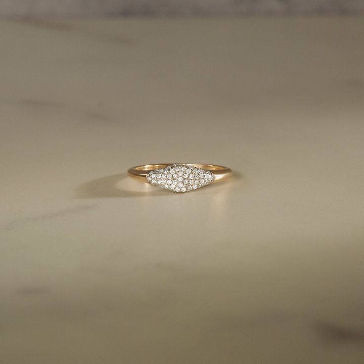 a yellow gold ring with three small diamonds on the top and bottom, sitting on a marble surface