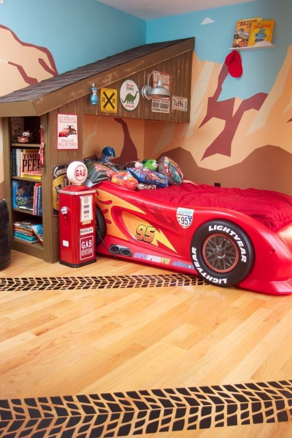 a child's bedroom with a red race car bed and bookcase in the corner