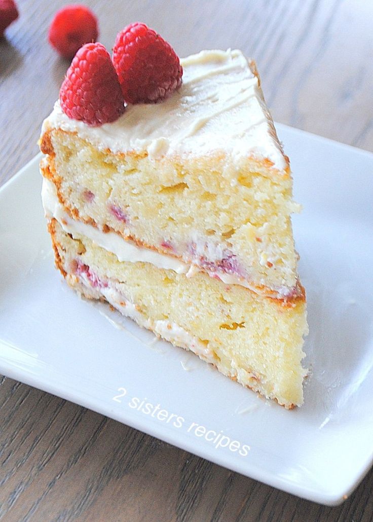 a piece of cake with white frosting and raspberries on top