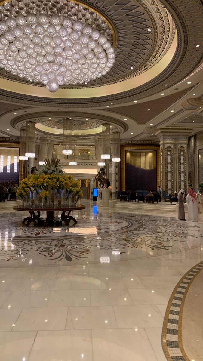 the inside of a hotel lobby with chandelier and flower arrangement on the center table