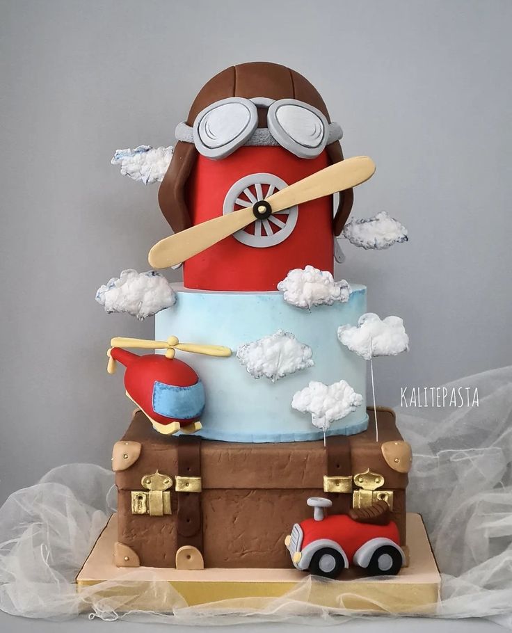 a cake that is shaped like an airplane and has clouds on it, with a red car in the middle