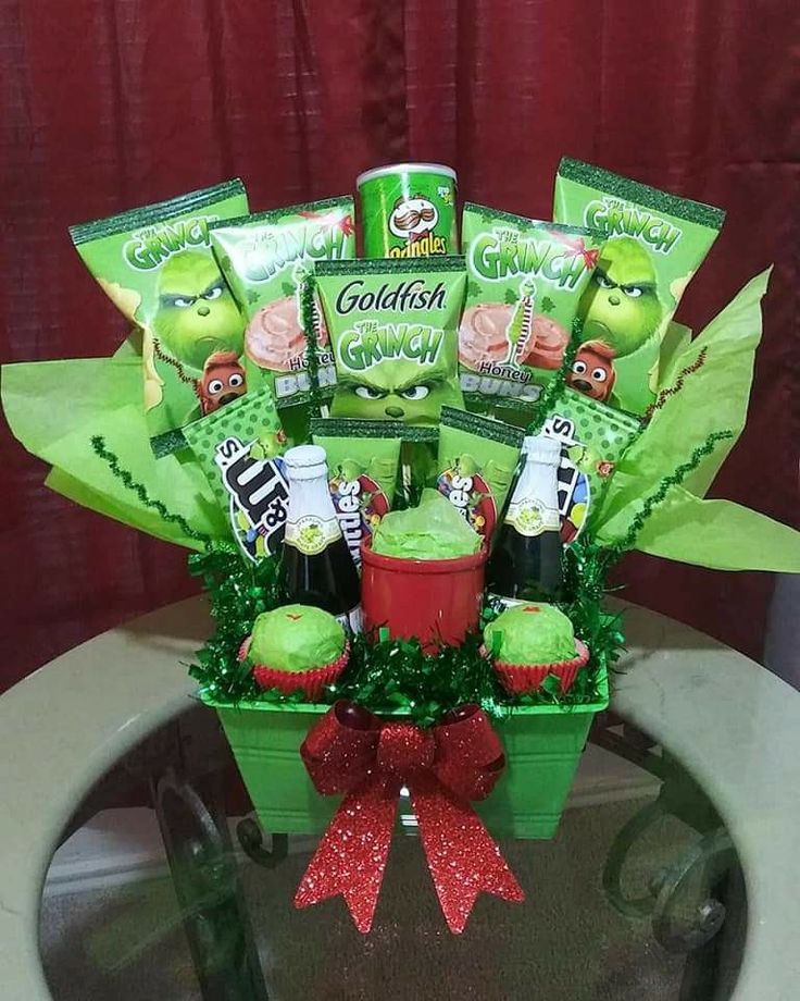 a green basket filled with candy and candies on top of a table next to a red bow