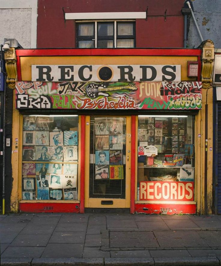 an old record store with many records on it's front window and windows covered in graffiti