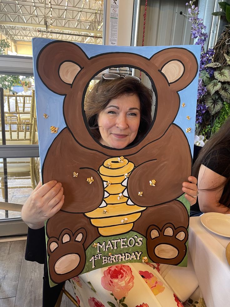 a woman holding up a teddy bear cutout with the words mateo's birthday written on it