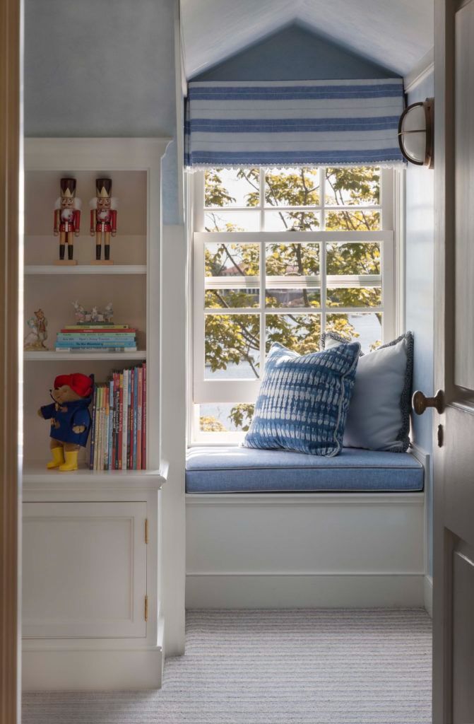 a window seat in the corner of a room with bookshelves and stuffed animals