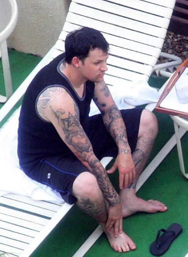 a man with tattoos sitting on the ground