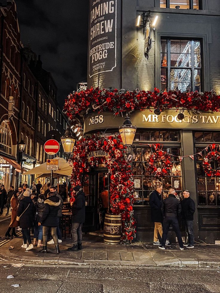 people are standing in front of a store decorated with red and gold christmas garlands