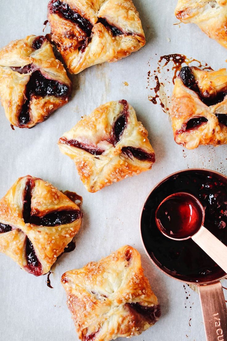 several pastries with jam on top and a spoon next to them