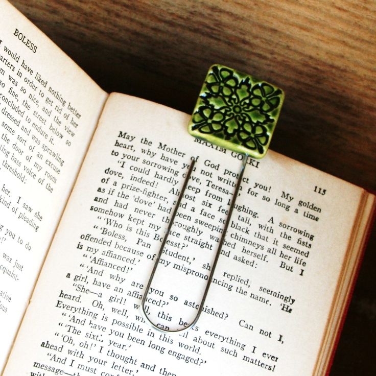 an open book with a green brooch sitting on top of it