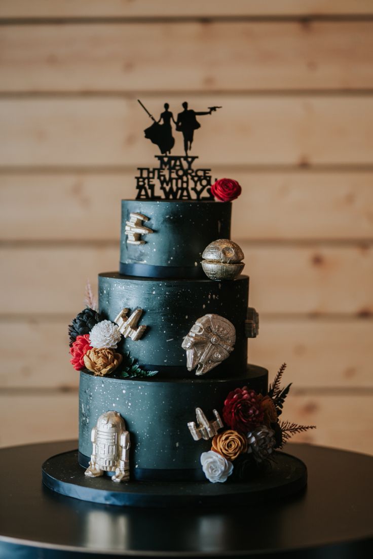 a three tiered blue wedding cake with star wars decorations on the top and sides