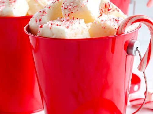 two red mugs filled with white chocolate and sprinkles