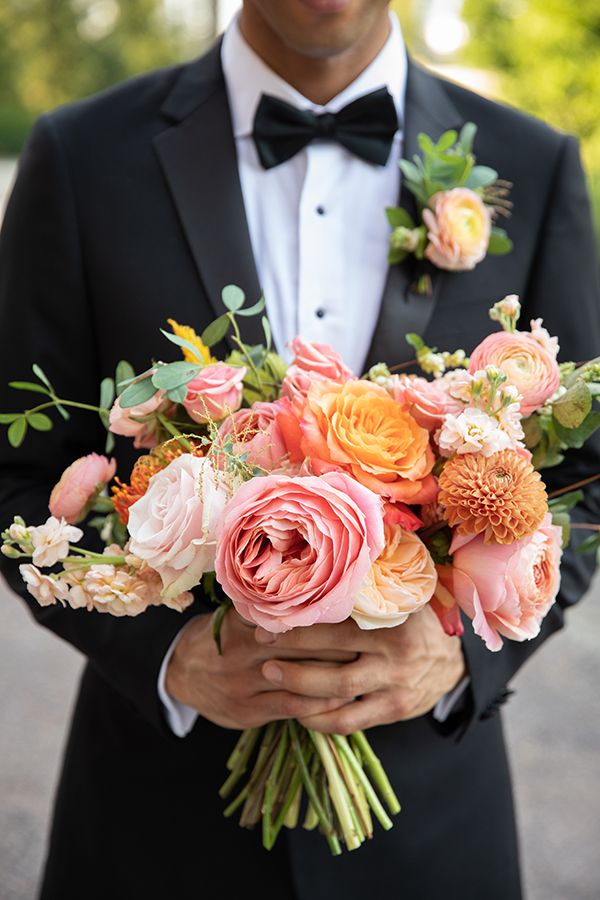 a man in a tuxedo holding a bouquet of flowers